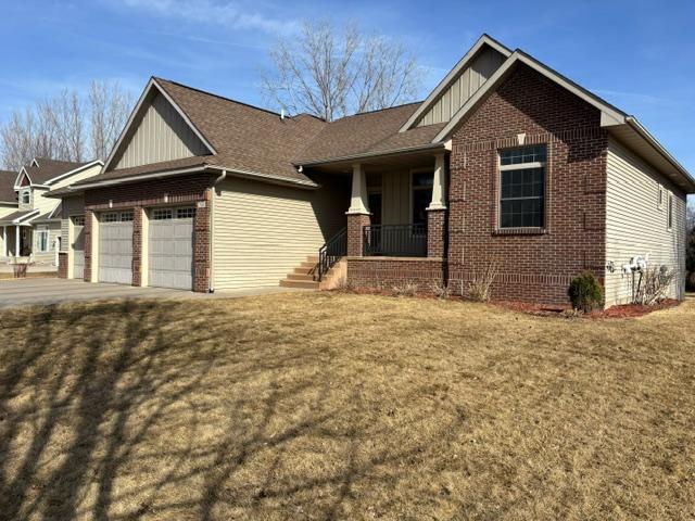 craftsman inspired home with brick siding, concrete driveway, board and batten siding, a front yard, and a garage