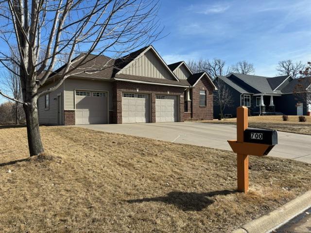 view of front of home with a garage, driveway, board and batten siding, and brick siding