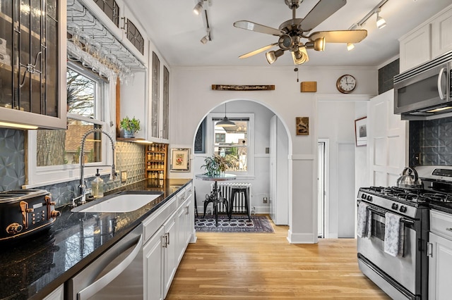 kitchen with rail lighting, stainless steel appliances, ceiling fan, and a sink