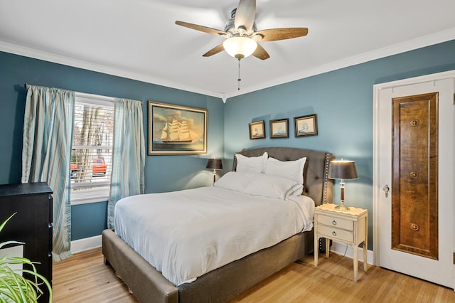 bedroom featuring ceiling fan, ornamental molding, baseboards, and wood finished floors