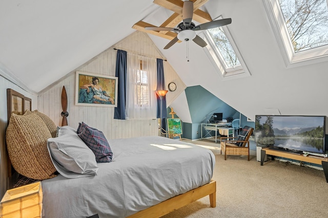 bedroom with wooden walls, lofted ceiling with skylight, ceiling fan, and carpet floors