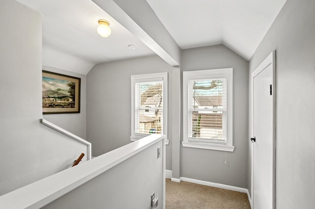 hall with light colored carpet, lofted ceiling, baseboards, and an upstairs landing