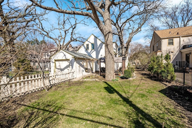 view of yard with an outdoor structure, an attached garage, and fence