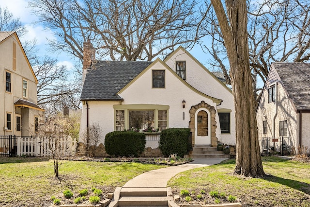 view of front of property with a chimney, a shingled roof, a front lawn, and fence
