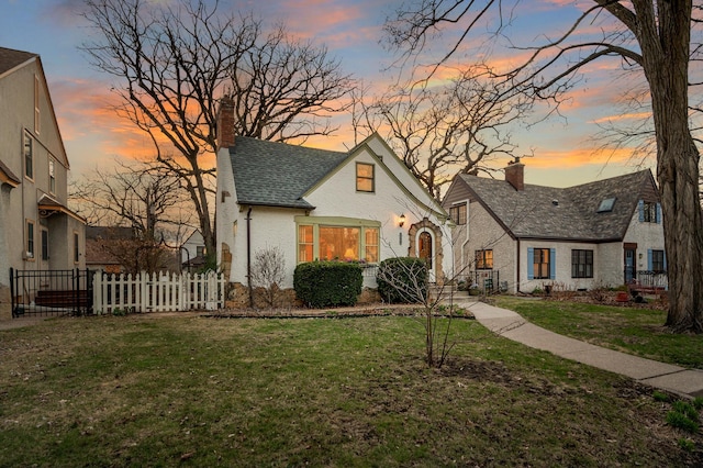 view of front of home featuring roof with shingles, fence, brick siding, a yard, and a chimney
