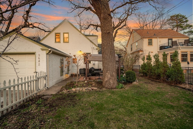 back of property with a lawn, an attached garage, a patio area, stucco siding, and a fenced backyard