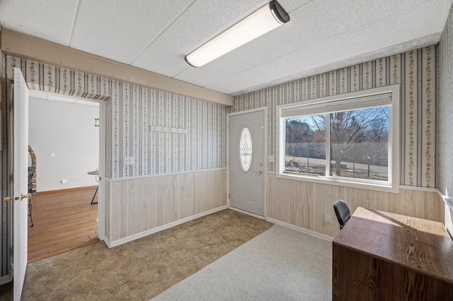 foyer entrance with wallpapered walls, baseboards, and wainscoting