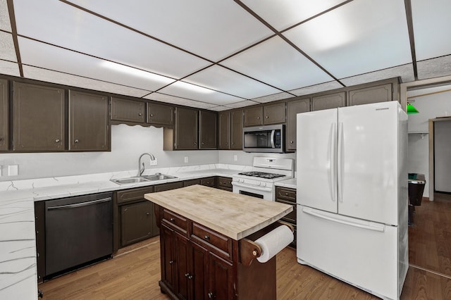 kitchen with light wood finished floors, stainless steel appliances, a sink, wood counters, and dark brown cabinets