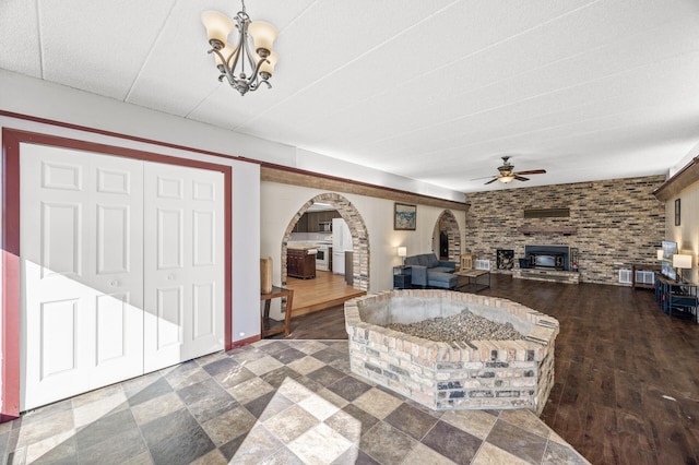 living room featuring arched walkways, wood finished floors, and ceiling fan with notable chandelier