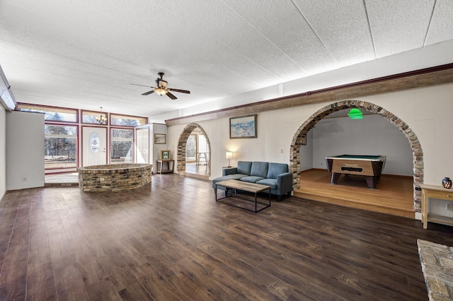 living area with a ceiling fan, arched walkways, dark wood-type flooring, and pool table