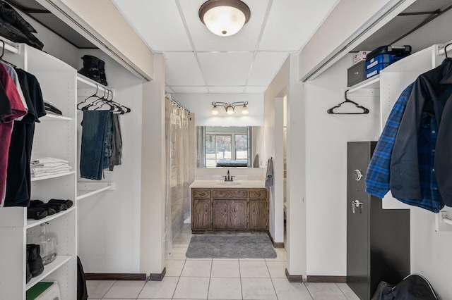 spacious closet with light tile patterned floors, a sink, and a paneled ceiling