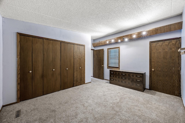 unfurnished bedroom with carpet, a textured ceiling, visible vents, and a closet