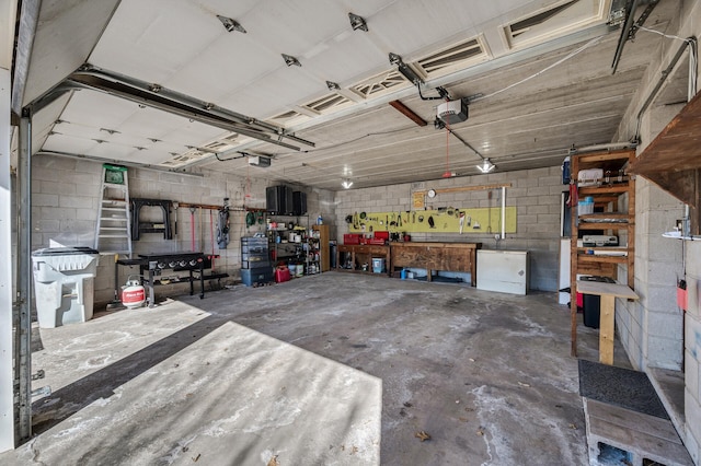 garage featuring a workshop area, concrete block wall, and a garage door opener