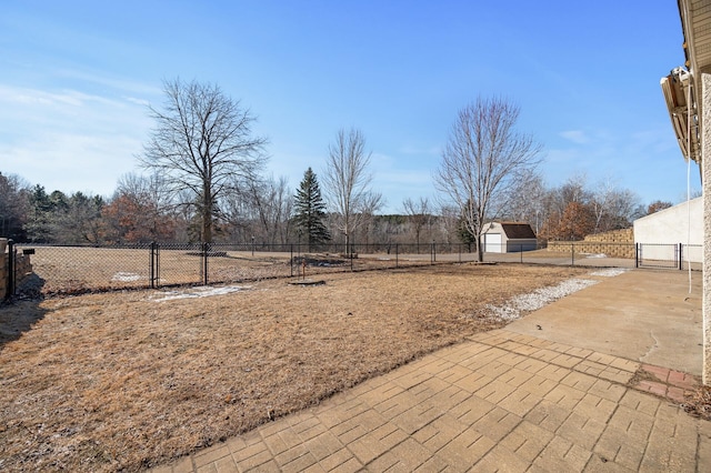 view of yard featuring a storage shed, a gate, fence, and an outbuilding