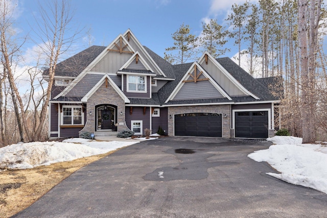 craftsman-style home with a garage, board and batten siding, driveway, and a shingled roof