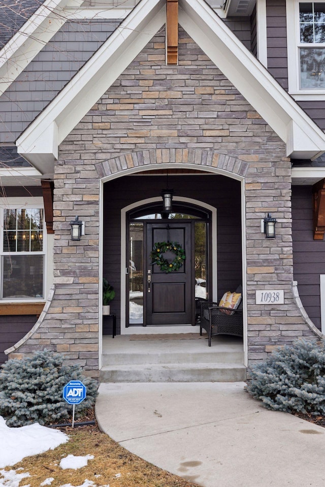 entrance to property featuring stone siding and covered porch