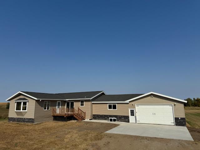 single story home featuring concrete driveway, a deck, and an attached garage