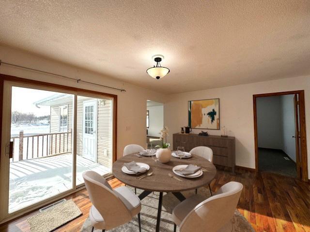 dining space with a textured ceiling, visible vents, and wood finished floors