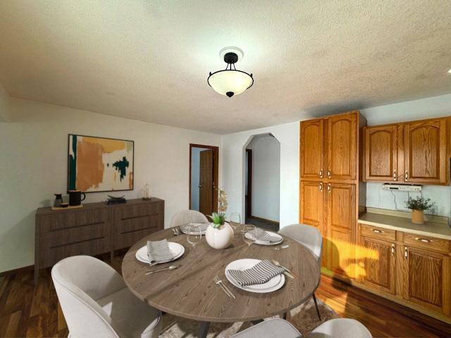 dining room with arched walkways, dark wood-style flooring, and a textured ceiling