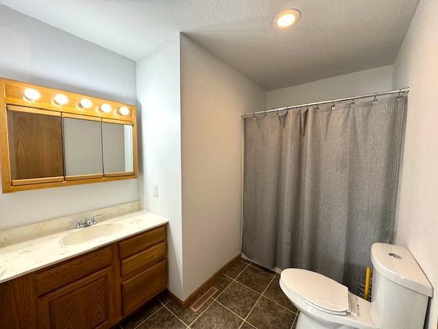 bathroom featuring curtained shower, toilet, vanity, baseboards, and tile patterned floors