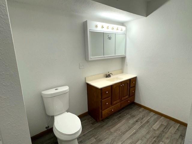 bathroom with baseboards, vanity, toilet, and wood finished floors