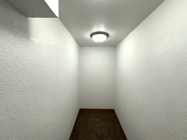 hall with carpet flooring and a textured wall