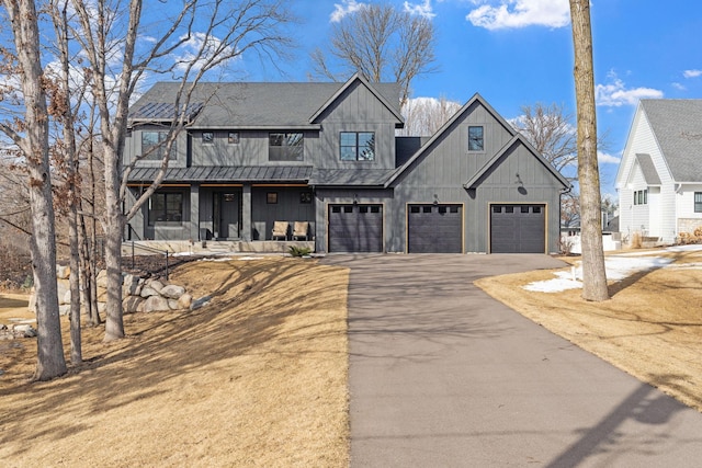 view of front of property featuring covered porch, driveway, an attached garage, and roof with shingles