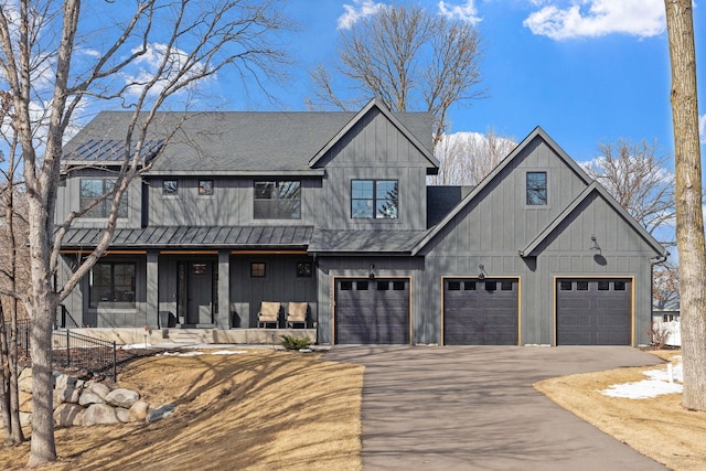 modern farmhouse with aphalt driveway, roof with shingles, a porch, and an attached garage