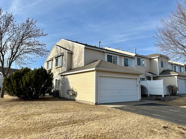 view of side of home featuring cooling unit, a yard, roof with shingles, concrete driveway, and a garage