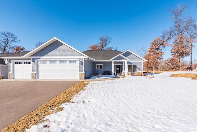 view of front of property featuring stone siding, driveway, and an attached garage