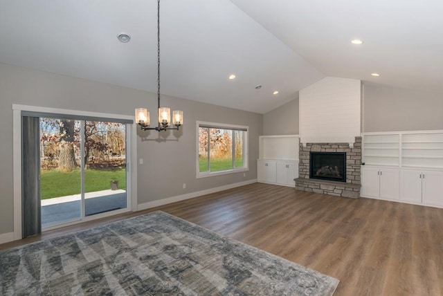 unfurnished living room featuring lofted ceiling, an inviting chandelier, a stone fireplace, wood finished floors, and baseboards