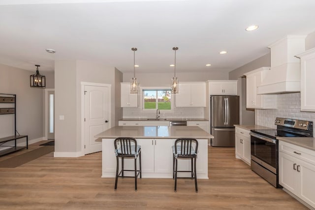 kitchen featuring a kitchen breakfast bar, backsplash, white cabinetry, a kitchen island, and appliances with stainless steel finishes