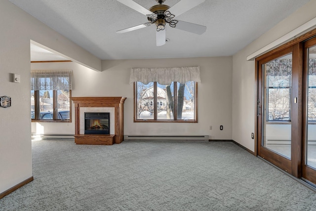 unfurnished living room with carpet, a baseboard radiator, plenty of natural light, and a glass covered fireplace