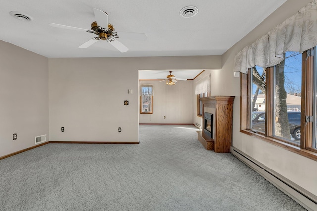 unfurnished living room with visible vents, a baseboard heating unit, light colored carpet, and a glass covered fireplace