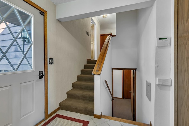 tiled foyer entrance with stairway and baseboards