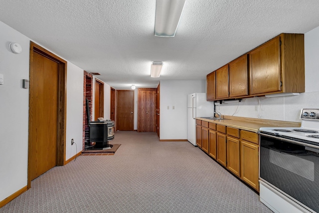 kitchen featuring a wood stove, white appliances, light carpet, and brown cabinetry