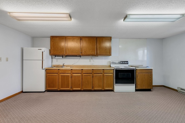 kitchen with a sink, electric stove, light countertops, freestanding refrigerator, and brown cabinets