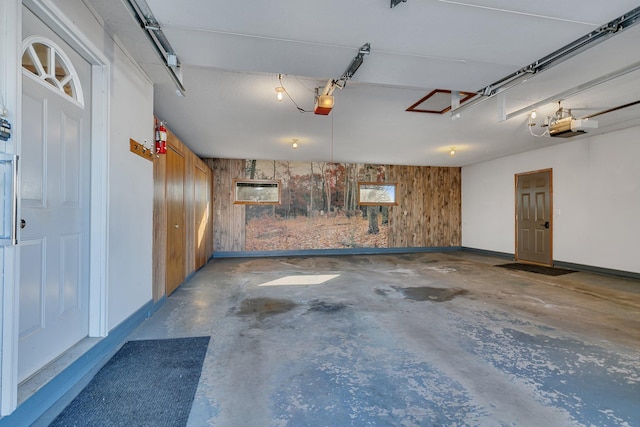 garage featuring a garage door opener, wood walls, and baseboards