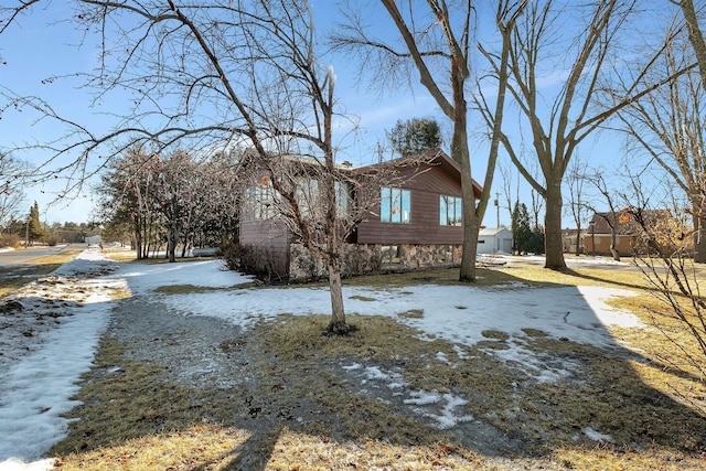 snow covered property with stone siding