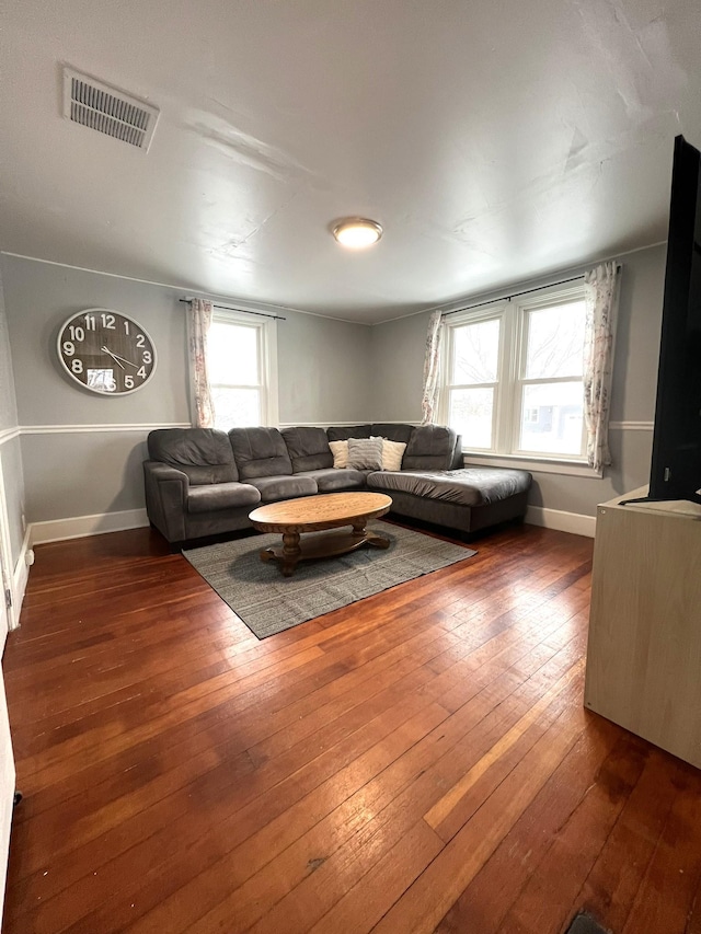 living room featuring hardwood / wood-style flooring, baseboards, and visible vents