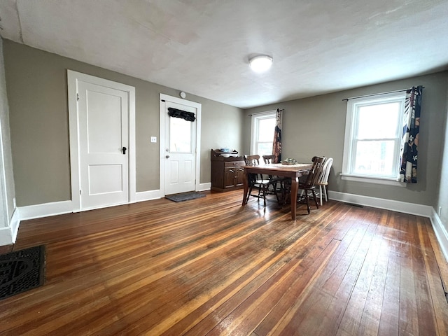 dining room with baseboards, dark wood finished floors, visible vents, and a healthy amount of sunlight