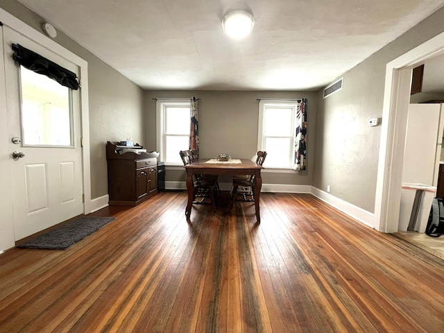 dining area with a healthy amount of sunlight, visible vents, and dark wood-type flooring