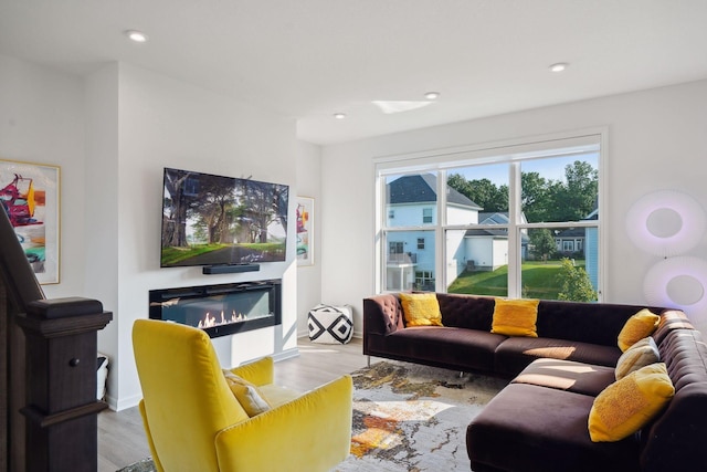 living room featuring wood finished floors, a glass covered fireplace, and recessed lighting