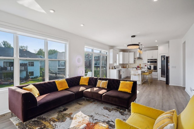 living area featuring baseboards, recessed lighting, and light wood-style floors