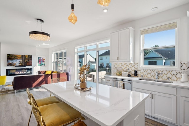 kitchen with a sink, white cabinets, dishwasher, tasteful backsplash, and pendant lighting