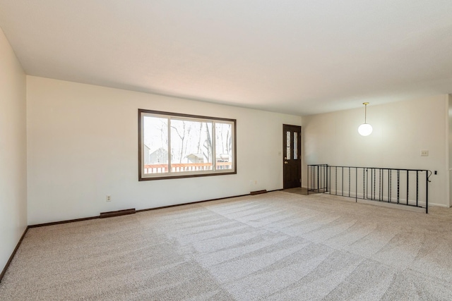 carpeted spare room featuring visible vents and baseboards