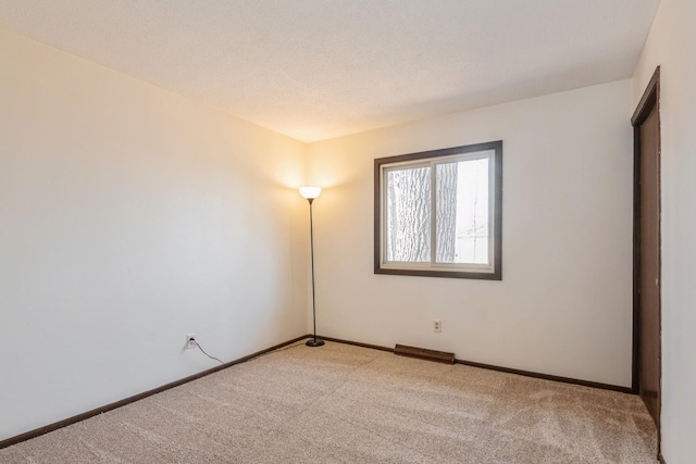 spare room featuring visible vents, baseboards, and carpet