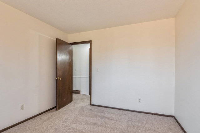 empty room with baseboards and light carpet