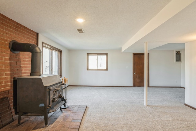 living room with a wood stove, a healthy amount of sunlight, baseboards, and a textured ceiling