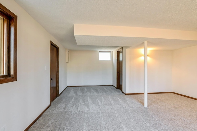 basement featuring carpet, baseboards, and a textured ceiling